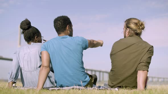 Back View of People Sitting on Meadow and Pointing at Horizon