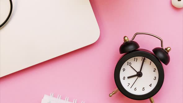 Laptop and White Notepad with Pen and Black Alarm Clock Arrows Point to