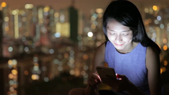 Woman looking on cellphone at night 