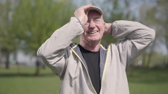 Positive Mature Man Putting the Cap on the Head, Protecting Eyes From the Sun Rays