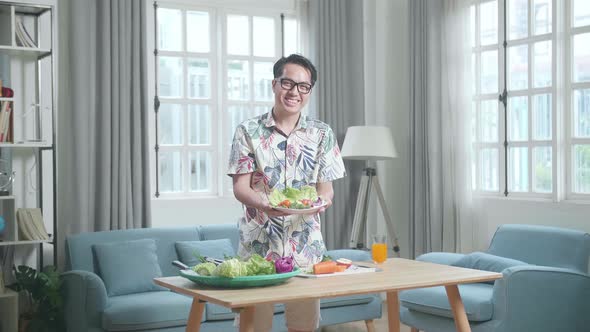 Smiling Asian Man Showing A Dish Of Healthy Food To Camera At Home