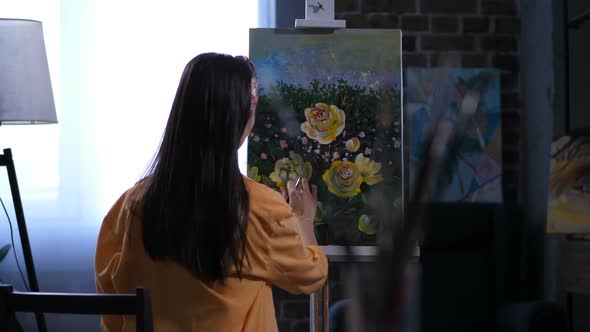 Female Artist Applying Final Touches To Painting