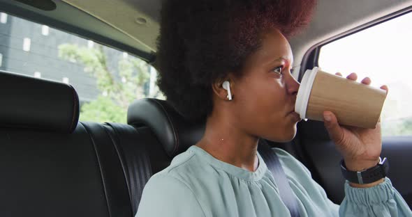 African american businesswoman drinking takeaway coffee in car