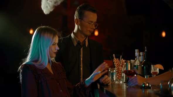 A Couple Talking By the Stand in the Bar - the Bartender Hands Them Cocktails