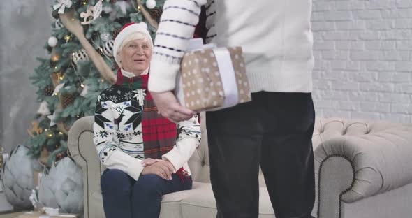 Caucasian Man Holding Gift Box Behind His Back, Focus Changes To Surprised Senior Woman Smiling and