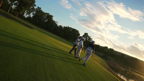 4K Group of Asian man golfer walking on golf course with talking together at summer sunset