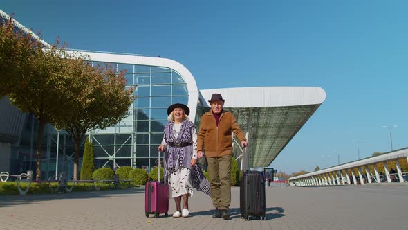 Stylish Retired Family Couple Granny Grandfather Walking with Luggage Suitcase Bags to Airport Hall