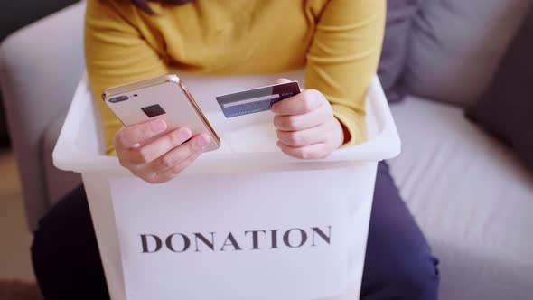 Detail of female hands making a donation with a credit card.