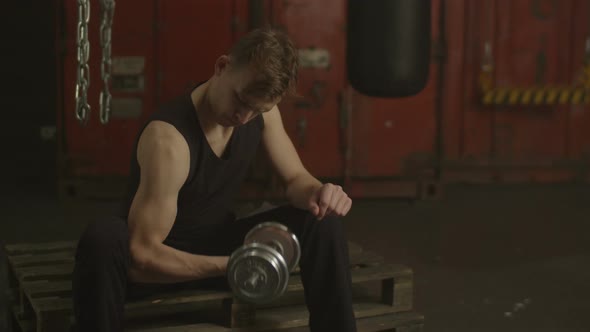 Muscular Man Exercising Biceps in Gym with Dumbbells