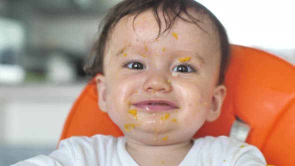 Closeup of the Face of a Beautiful Child Smeared with Food Who Sits on a Chair and Indulges Pulls