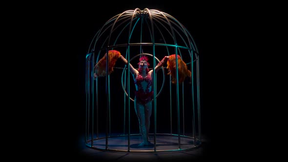 Actress Rotates on the Air Hoop in a Cage. Black Background. Slow Motion