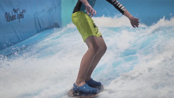 Teenager is Riding Surf Board on Wave Simulator Indoors