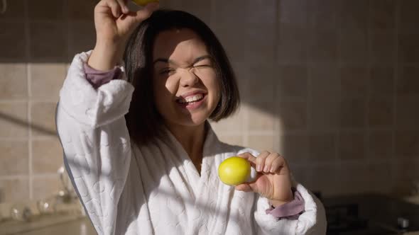 Cheerful Relaxed Little Woman Having Fun Posing with Healthful Vitamin Lemons in Kitchen at Home