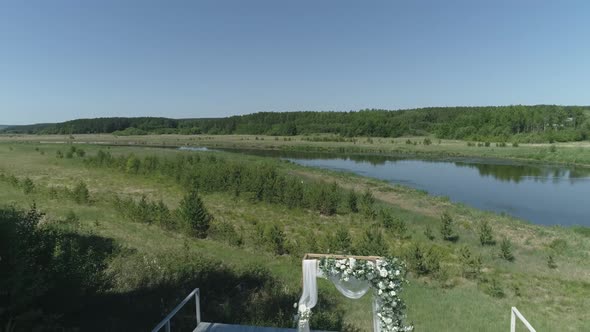 Aerial view of wedding arch on the pier by the river next to the forest 11