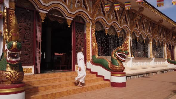 Young woman tourist go down the stairs in Buddhist Wat Luang Temple, dragons. Travel in Pakse, Laos