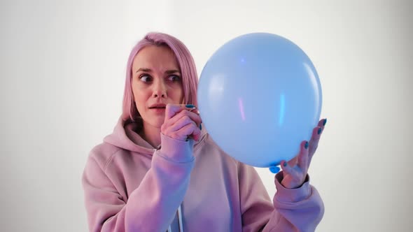 Woman with Pink Hair Bursting a Balloon