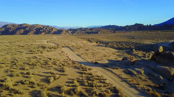 Scenic aerial drone view of dirt road and rocky desert landscape.