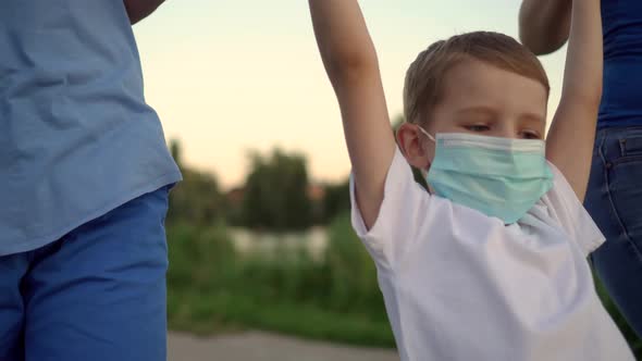 A Family with a Child in Medical Masks Walk Near the Lake