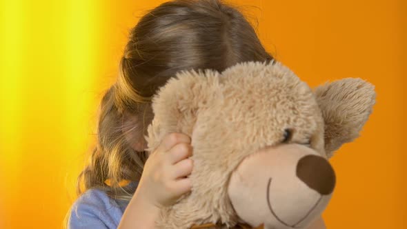 Adorable Preschool Girl Hiding Behind Plush Bear and Smiling to Camera, Play