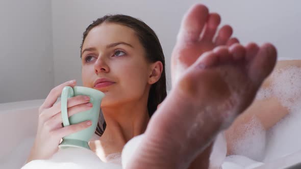 Woman drinking coffee while relaxing in a bathtub