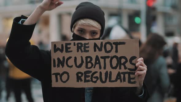 Womens March. Young Woman with Face Mask Protesting with Banner Sign - We Are Not Incubators To