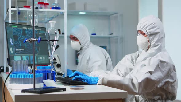 Team of Biologists in Coverall Working with Microscope and Computer alt
