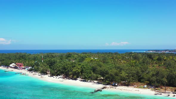 Tropical island with lush vegetation and palm trees forest by the blue turquoise sea washing white s