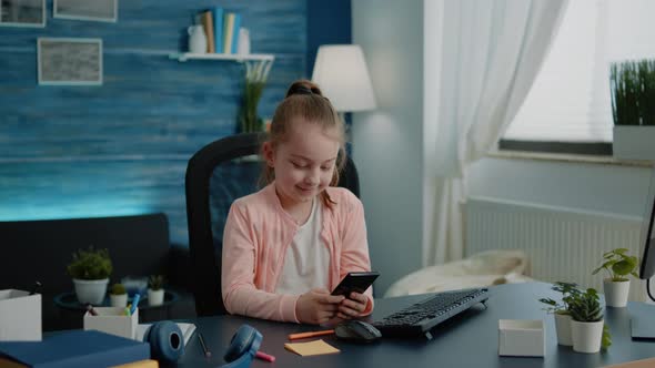 Young Girl Using Smartphone with Touch Screen at Desk