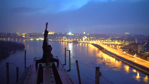 Young Man Practicing Yoga on the Edge of Bridge in the Evening, Doing Headstand