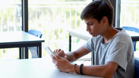 Happy schoolboy using digital tablet in classroom