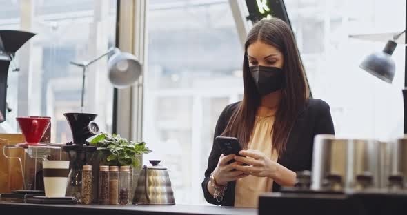 Customer Woman in Medical Protection Mask Paying Using NFC Technology with Phone and Credit Card