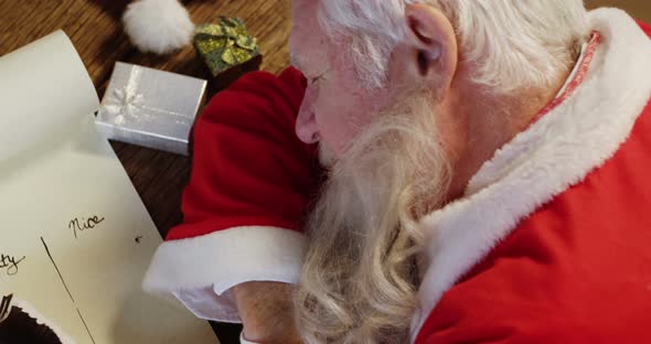Santa claus sleeping at desk while writing a letter with a quill 4k