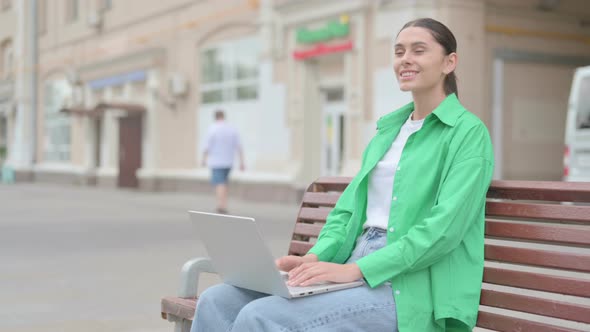 Agree Hispanic Woman Shaking Head in Approval While Sitting on Bench Outdoor