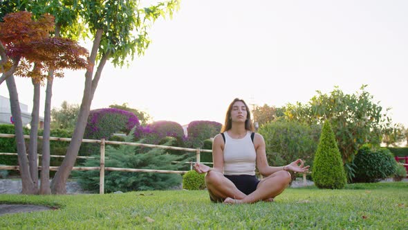 Wide shot of a young woman doing yoga and mindfulness in a garden