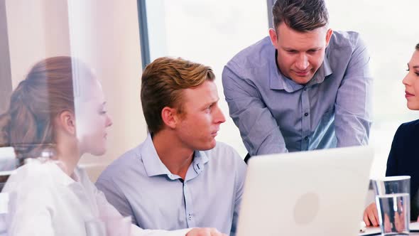 Executives discussing over laptop