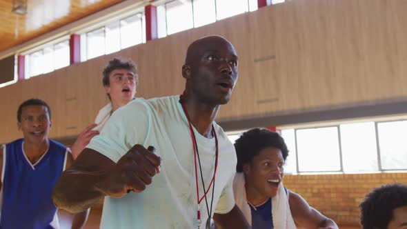 Diverse male basketball team and coach celebrating together