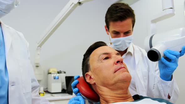 Dentist examining a male patient with dental tool