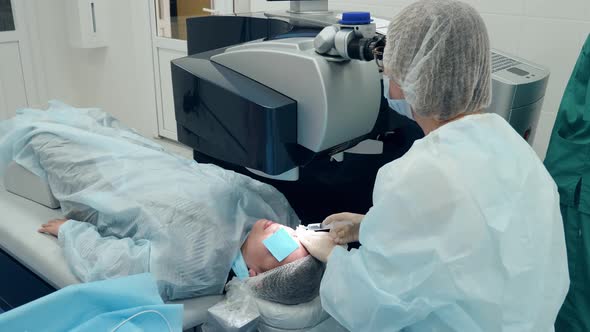 Doctor is Looking Into a Microscope While Operating Patient's Eye