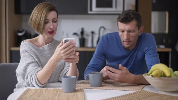 Absorbed Caucasian Adult Couple Surfing Social Media on Smartphones Ignoring Each Other