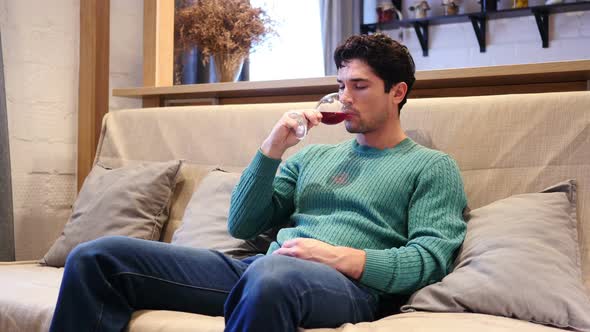 Pensive Young Man Drinking Red Wine at Home Thinking