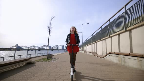 Young Blonde Woman Rides Electric Scooter