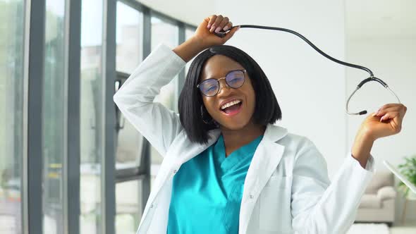 Happy Young African American Woman Doctor Dancing with a Stethoscope in the Hospital