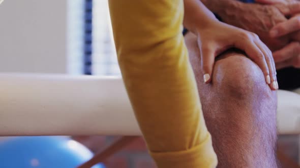 Physiotherapist giving knee massage to senior patient 4k