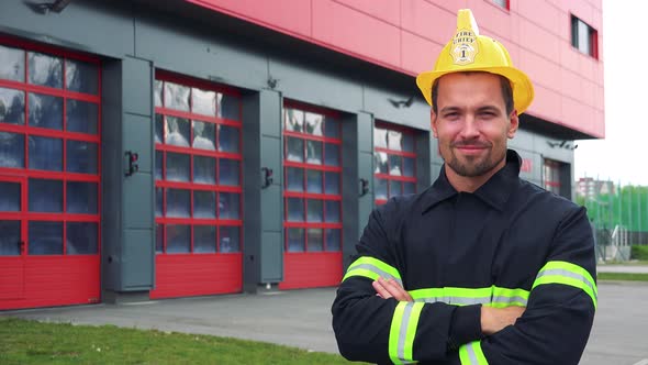 A Young Firefighter Smiles at the Camera and Folds His Hands Across His Chest - a Fire Station