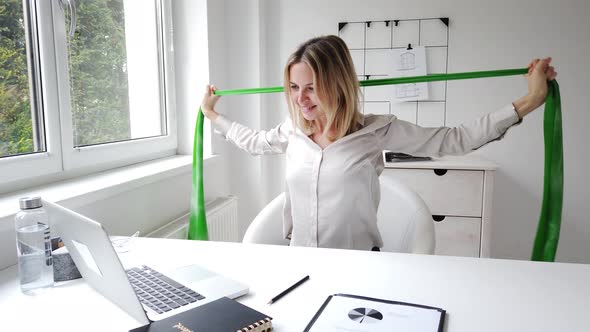 Businesswoman exercising with resistance band sitting at desk