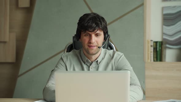 Man with Headset and Laptop Computer Having Video Conference at Office