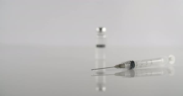 Empty Syringe and Vaccine on a White Surface