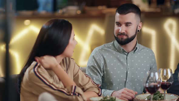 Man and Woman Sitting at Table with Food and Drink in Restaurant