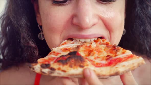 Young Cute Italian-looking Woman in a Red Dress Eagerly Eating and Enjoying Italian Pizza While in a