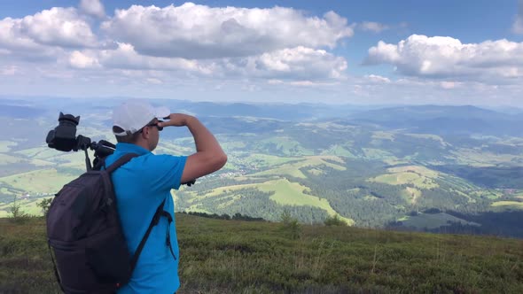 A man photographs a mountain landscape while hiking in the mountains.